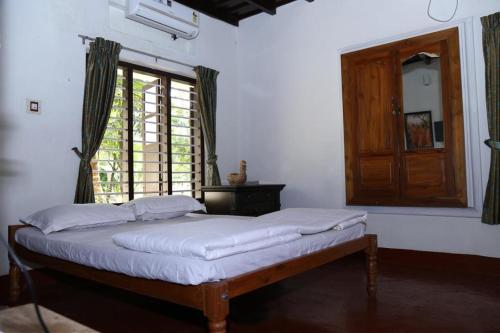 a bed sitting in a room with a window at Aqualillies Water Front Heritage Homestay in Kumarakom