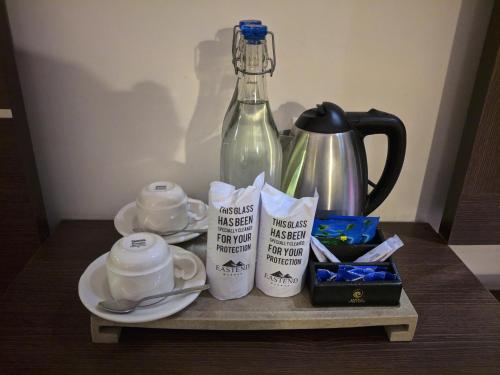 a table with cups and a bottle on it at Eastend Munnar in Munnar