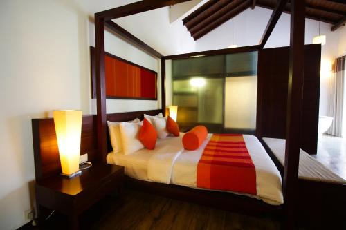 a bedroom with a large bed with orange pillows at The Calm Resort & Spa in Pasikuda