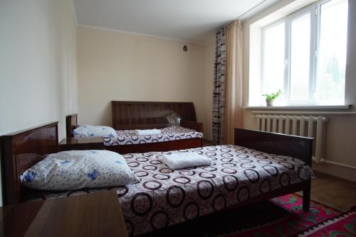 two beds in a small room with a window at EcoUlan in Kochkor
