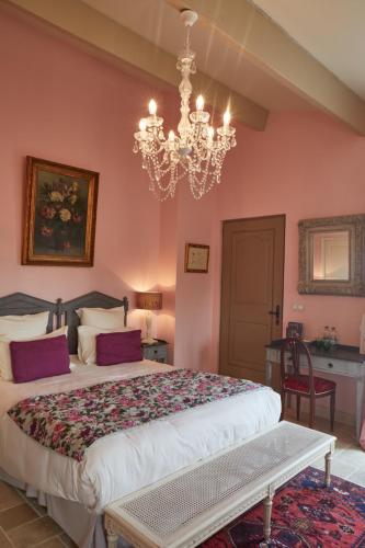 a bedroom with a large bed and a chandelier at Le Pré de l'Aube in Montjoyer