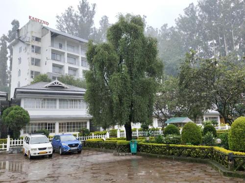 two cars parked in a parking lot in front of a building at Eastend Munnar in Munnar