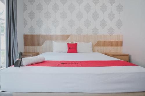 a bedroom with a large white bed with red pillows at RedDoorz Syariah near RSUD Kolonel Abundjani Bangko in Bangko