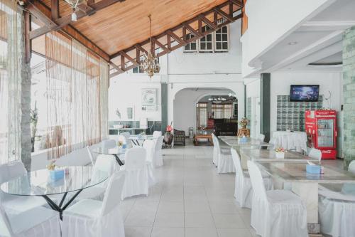 a dining room with white chairs and tables and a room at RedDoorz Syariah near RSUD Kolonel Abundjani Bangko in Bangko