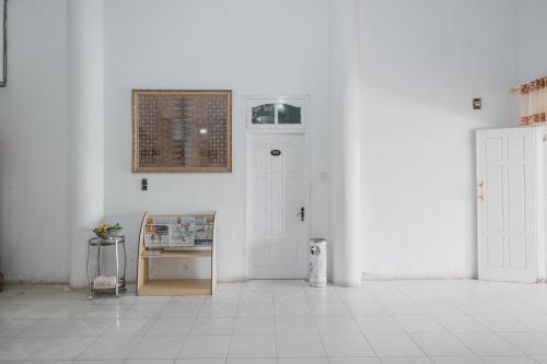 a white room with a door and a tile floor at RedDoorz Syariah near RSUD Kolonel Abundjani Bangko in Bangko