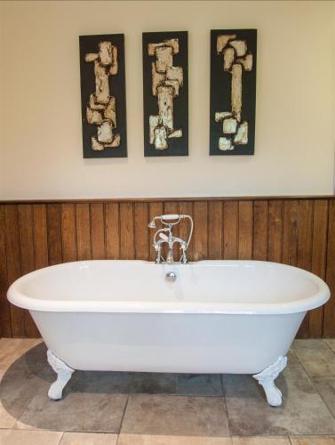 a white bath tub in a bathroom with three pictures on the wall at Exeter Court Hotel in Exeter