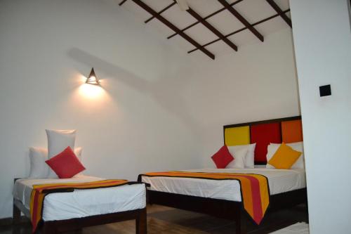 Habitación con 2 camas y almohadas coloridas. en Sigiri Resort, en Sigiriya