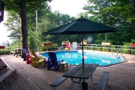 a table with an umbrella next to a swimming pool at Stouffermill Bed & Breakfast in Algonquin Highlands