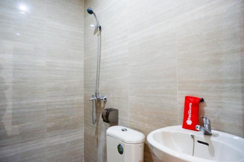 a bathroom with a sink and a toilet with a red bag at RedDoorz Syariah near RSUD Margono Purwokerto in Purwokerto