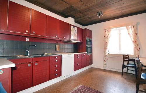eine große Küche mit roten Schränken und einem Fenster in der Unterkunft Awesome Home In Tidaholm With Kitchen in Älvstorp