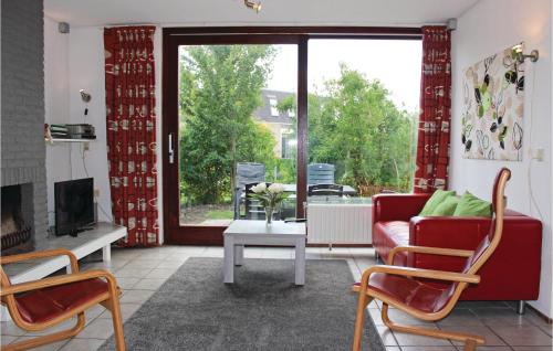a living room with a red couch and a fireplace at Beautiful Home In Nieuwvliet-Bad in Nieuwvliet-Bad