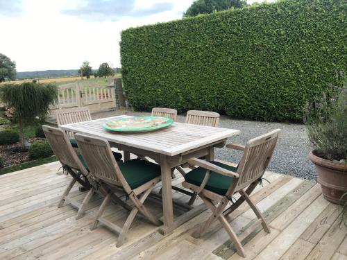 a wooden table and chairs on a wooden deck at La Maison d'Arc Chambres et Tables d'Hôtes in Frasnes-lez-Anvaing