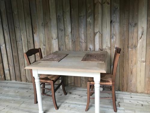 a table with two chairs and a wooden wall at La Maison d'Arc Chambres et Tables d'Hôtes in Frasnes-lez-Anvaing
