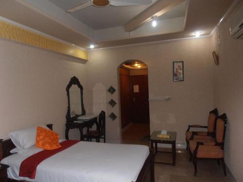 a bedroom with a bed and a chair and a mirror at Hotel The Leschanze in Lahore