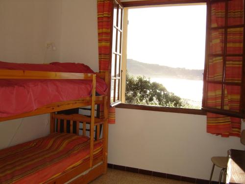 1 dormitorio con 2 literas y ventana en Maison de vacances avec vue imprenable sur la mer, en Calcatoggio
