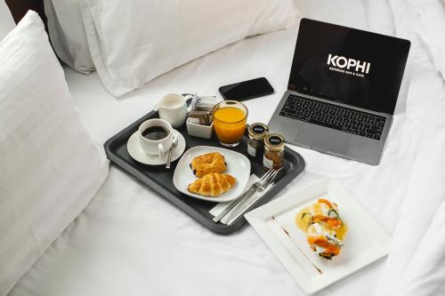 a tray with breakfast foods and a laptop on a bed at Residence26 in Yangon