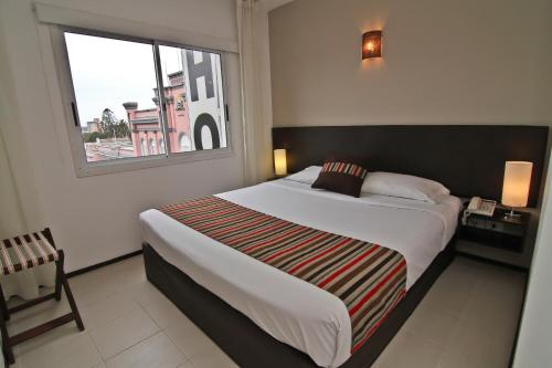 a bedroom with a large bed and a window at De la Plaza Hotel in Maldonado