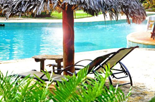 a chair and table next to a tree next to a pool at Las Puertas del Paraíso in Río San Juan