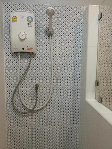 a shower with a hose attached to a wall in a bathroom at Chan Place Hotel in Nakhon Ratchasima