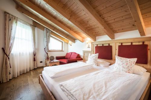 a bedroom with a large bed and a red couch at Piculin Alpin Apartments in San Martino in Badia