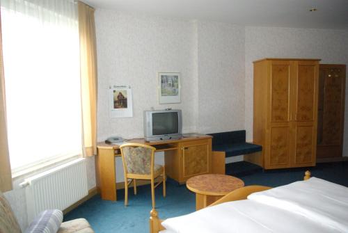 Habitación de hotel con cama y escritorio con TV. en Hotel Güldene Gabel, en Unterwellenborn
