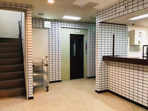 a bathroom with white tiled walls and a door at HOTEL Ra KAGOSHIMA in Kagoshima