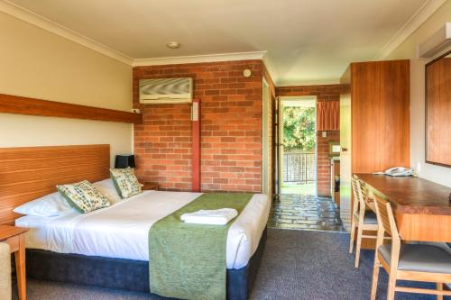 a bedroom with a bed and a brick wall at Murwillumbah Motor Inn in Murwillumbah