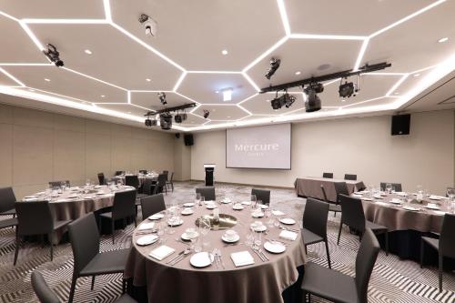 a conference room with tables and chairs and a screen at Mercure Ambassador Ulsan in Ulsan