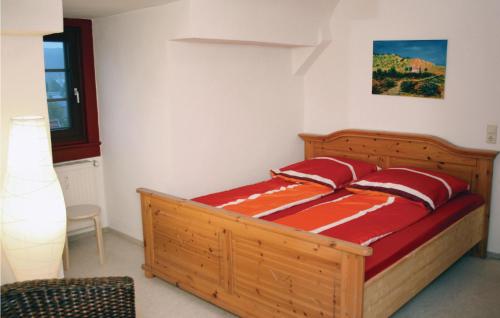 Schlafzimmer mit einem Holzbett mit roter Bettwäsche in der Unterkunft Beautiful Apartment In Tambach-dietharz With 3 Bedrooms And Wifi in Tambach-Dietharz