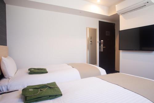 a hotel room with three beds and a flat screen tv at Hotel Kuretakeso Hiroshima Otemachi in Hiroshima