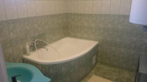 a bath tub in a bathroom with a sink at Zala Vendégház in Zalacsány