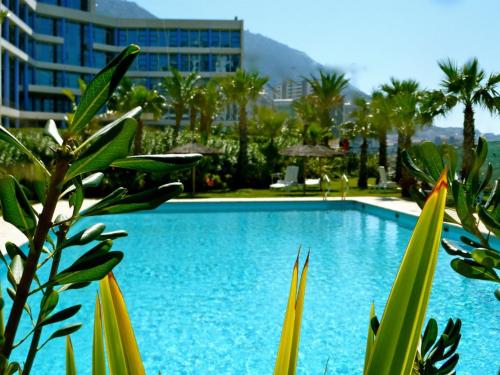 a blue swimming pool with palm trees and a building at Atlantic Suites Serviced Apartments in Gibraltar