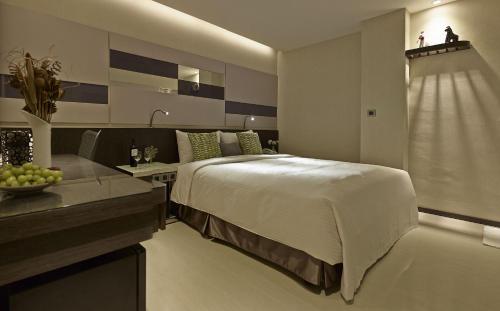 a bedroom with a bed and a desk with a bowl of fruit at Beauty Hotels Taipei - Hotel B7 in Taipei
