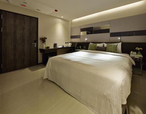 a bedroom with a large white bed and a desk at Beauty Hotels Taipei - Hotel B7 in Taipei