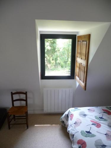 a bedroom with a bed and a window and a chair at Chambre d'hôtes Suite 53m2 ou Caravane vintage avec cuisine et salle de bains privées, B&B 53m2 Suite or Vintage caravan with private kitchen and bathroom in Pleumeur-Gautier