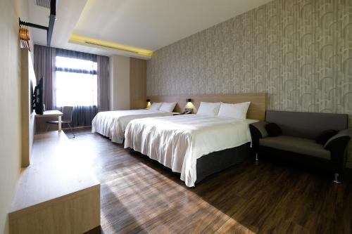 a hotel room with two beds and a chair at Yu Chun Hotel in Taichung