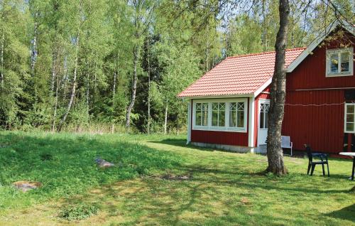 a red barn with a table and a chair in front of it at Holiday Home Knihult Häradsbäck in Knihult