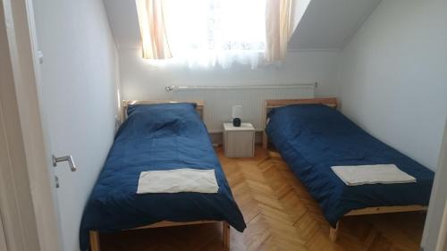 twee bedden in een kleine kamer met blauwe lakens bij Zala Vendégház in Zalacsány