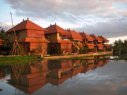 a row of houses with red roofs next to a body of water at Green Field Hotel and Restaurant in Ubud