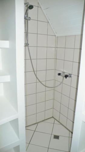 a shower with a hose in a white tiled bathroom at Sædding Strandvej (ID 119) in Esbjerg