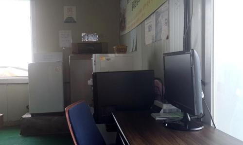 a desk with a computer monitor on a table at Minjoonggak in Seogwipo