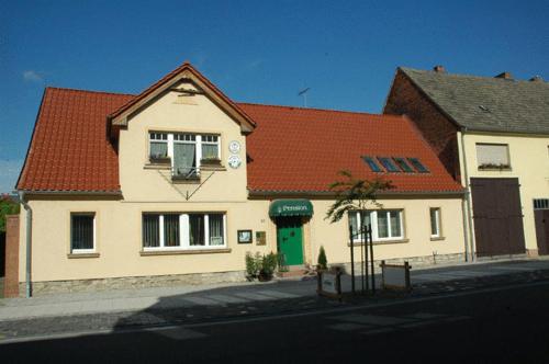 a white house with a red roof on a street at Hotel garni & Oma's Heuhotel 'Pension zur Galerie' in Barby