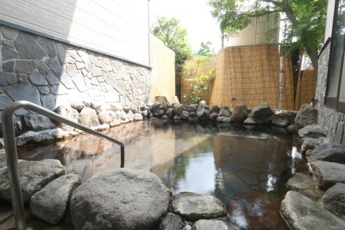 a pool of water next to a stone wall at Yufuin Yamaboushi in Yufuin