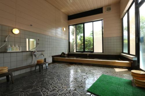 a bathroom with a toilet and a tub and a window at Yufuin Yamaboushi in Yufuin