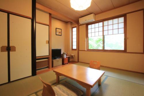 a living room with a wooden table and chairs at Yufuin Yamaboushi in Yufuin