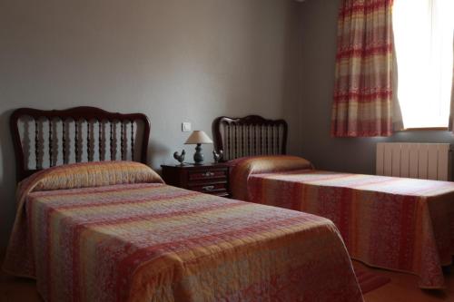 1 dormitorio con 2 camas y ventana en Los Gallos en Sobremazas