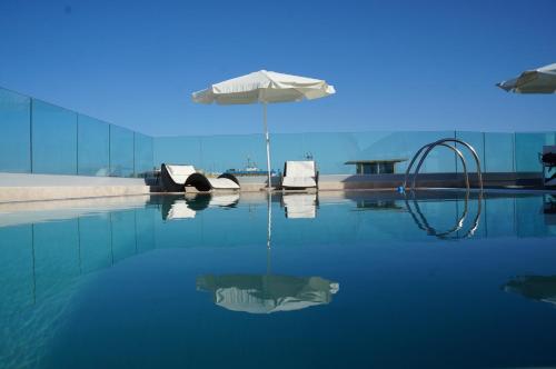 una piscina d'acqua con ombrellone e sedie di Hotel L'Approdo ad Anzio