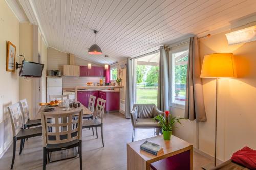 een keuken en een woonkamer met een tafel en stoelen bij Lagrange Grand Bleu Vacances – Résidence Port Lalande in Castelmoron-sur-Lot