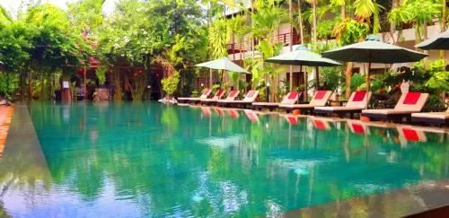 una piscina con sedie e ombrelloni di La Niche D'angkor Boutique Hotel a Siem Reap