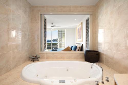 eine Badewanne im Bad mit einem großen Fenster in der Unterkunft Pavillion 17 - Waterfront Spacious 4 Bedroom With Own Inground Pool And Golf Buggy in Hamilton Island